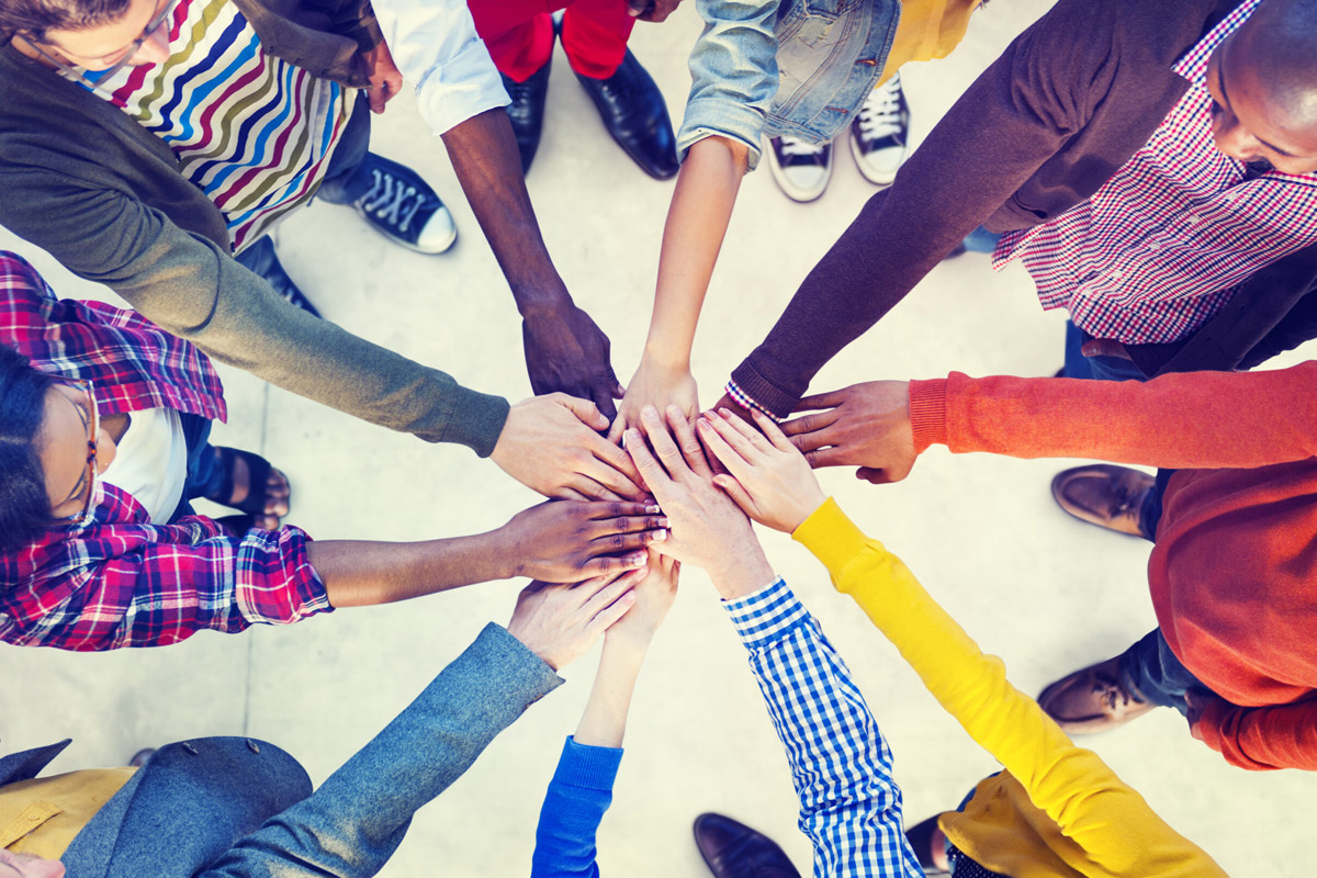 Viele Hände treffen sich in der Mitte, Symbolbild 'Teamwork'.